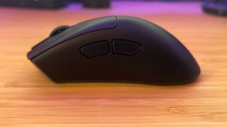 Razer DeathAdder V3 Hyperspeed gaming mouse shown from the side to display side buttons while sitting on a wooden desk