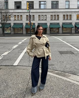 woman wearing short trench jacket and baggy jeans with stiletto heels