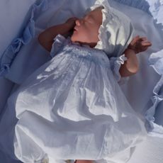 Isabel Vesterberg wearing a bonnet and dress in a bassinet