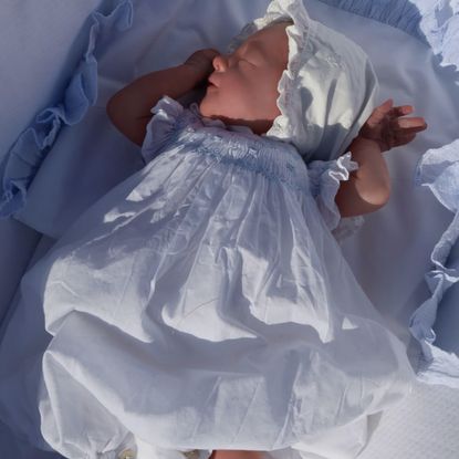 Isabel Vesterberg wearing a bonnet and dress in a bassinet