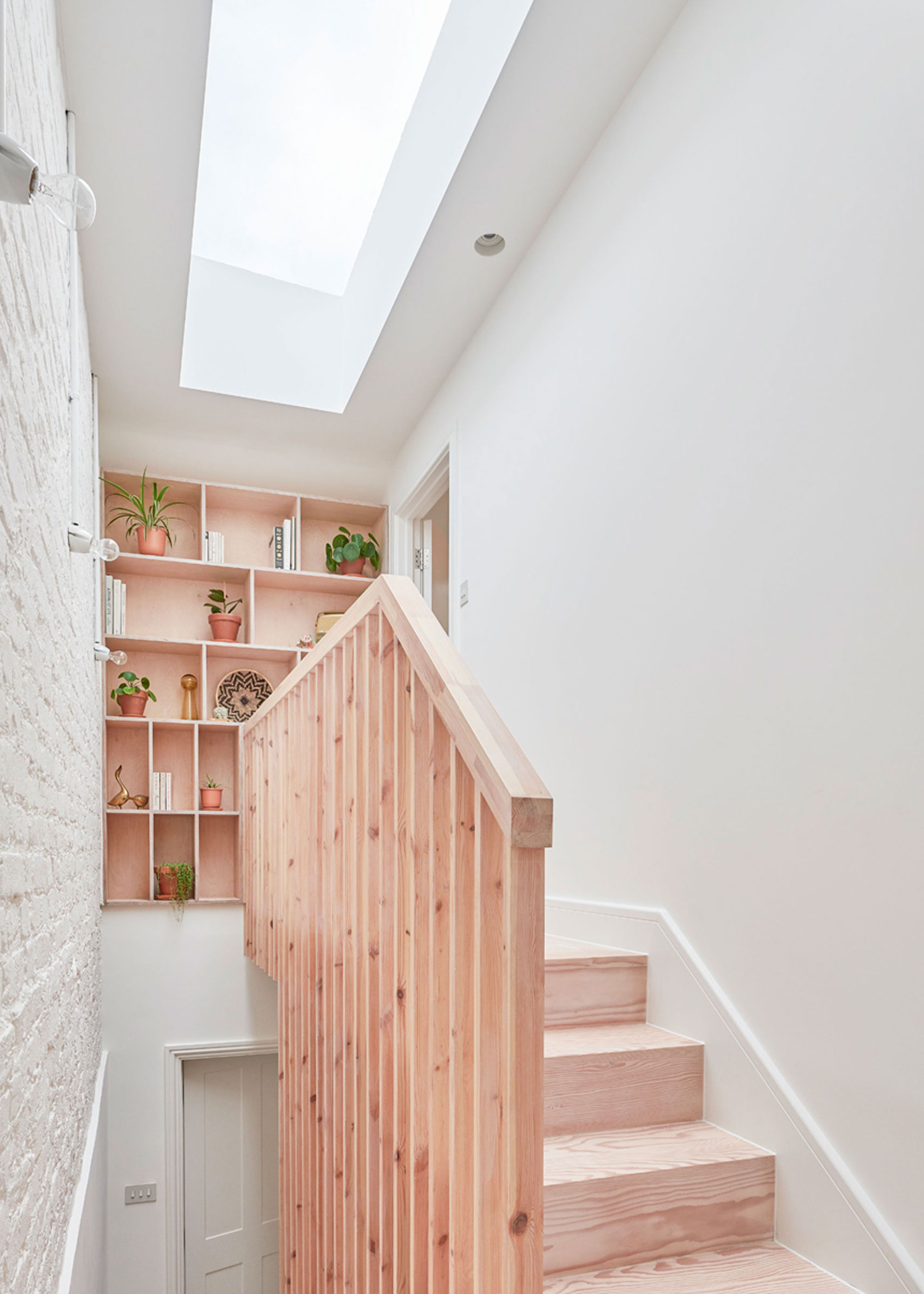 stripped wooden staircase with landing shelving