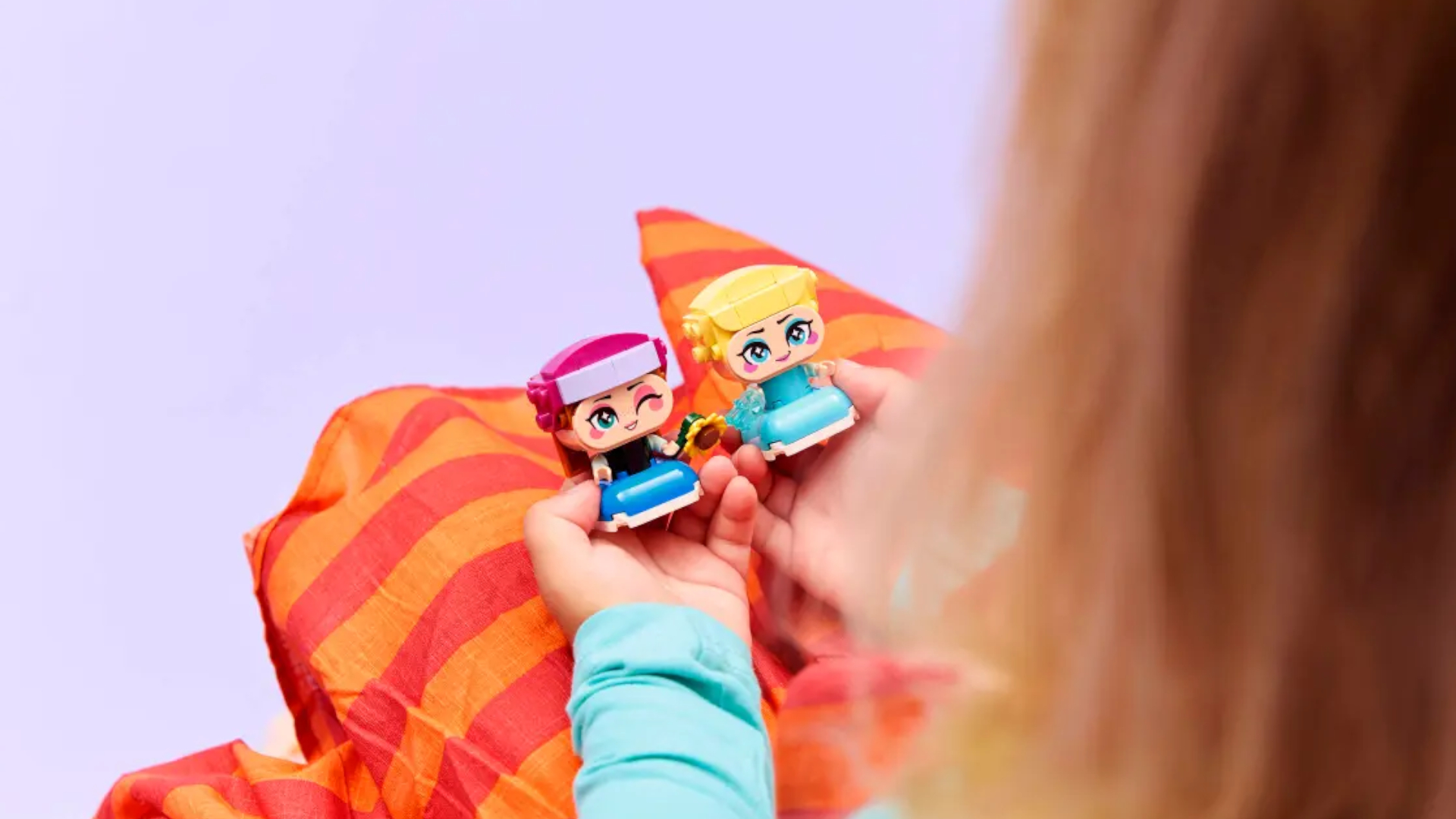 A child holding Lego Mini Elsa & Anna in their lap