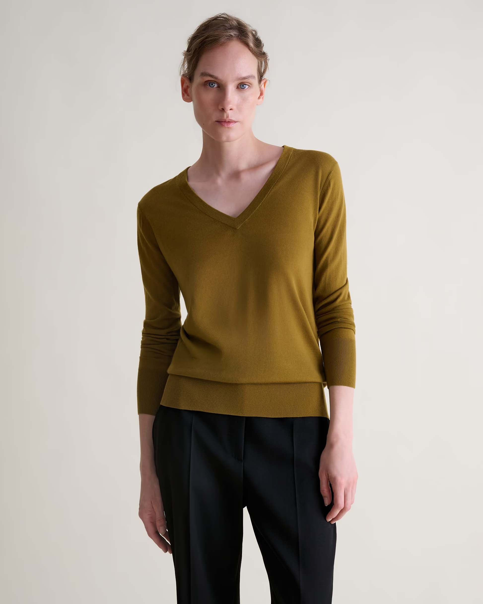A model wearing a green Rise &amp;amp; Fall v-neck jumper.