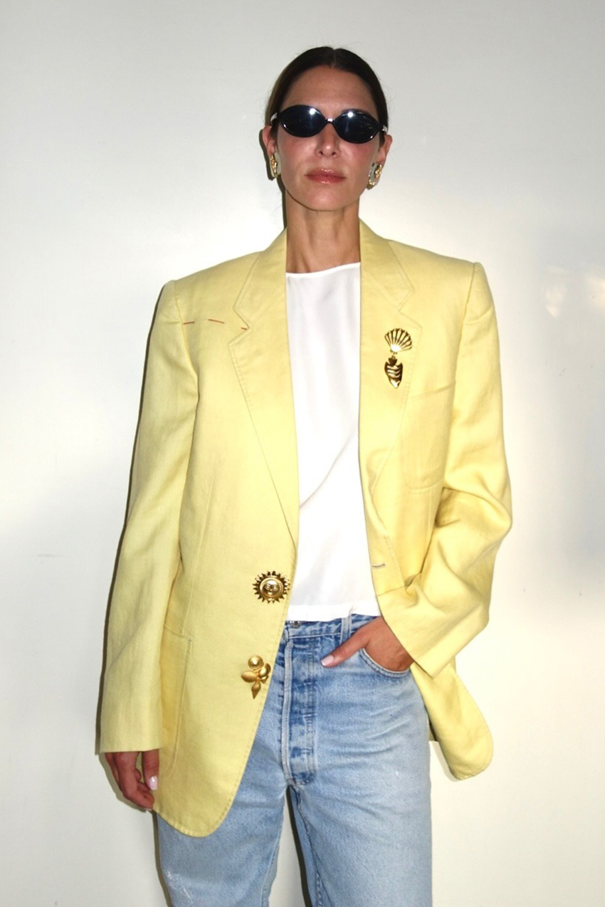 influencer @jen_wonders wearing a yellow blazer with gold brooches and blue jeans