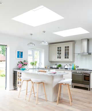kitchen with white wall and counter and stools on wooden floor