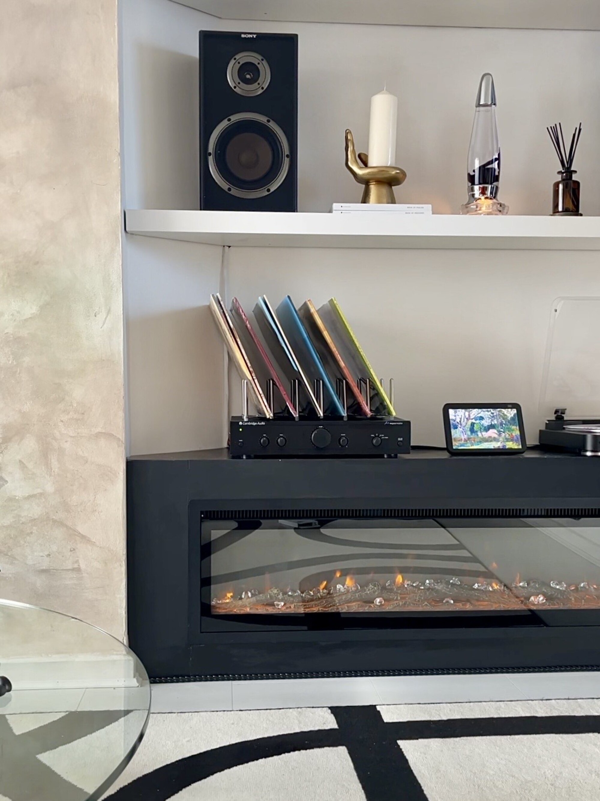 A living room with a modern electric fireplace and alcove shelving displaying decor, vinyls, and a record player