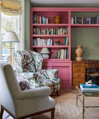 traditional living room with pink painted bookshelves and an antique desk