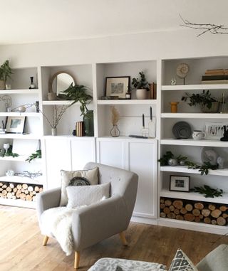 a gray chair, wooden floor, and a BILLY bookcase hack in a living room with white paint and stylish accessories