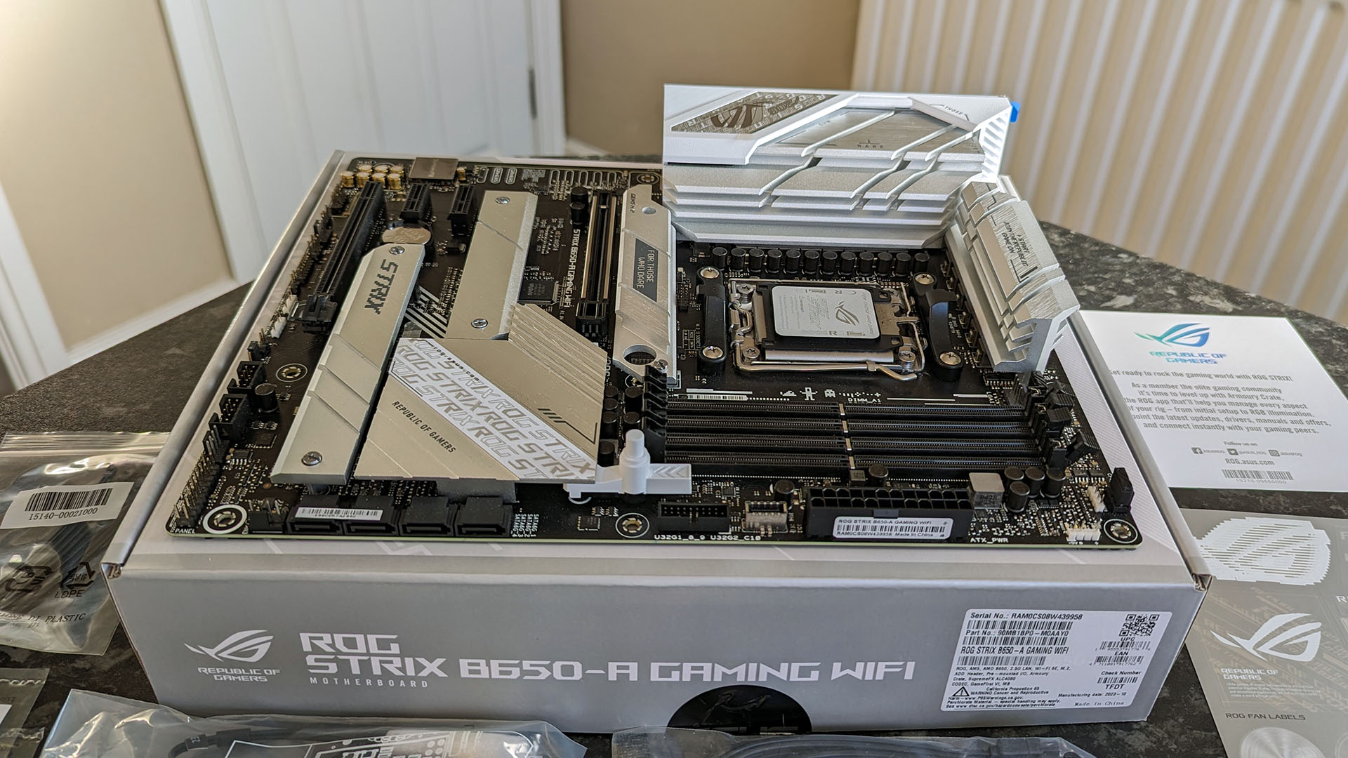 ASUS ROG STRIX B650-A Gaming Wifi motherboard seated on top of its retail packaging with accessories unboxed