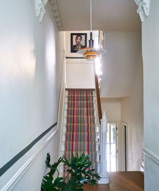 hallway with white walls, striped stair runner, wooden floors