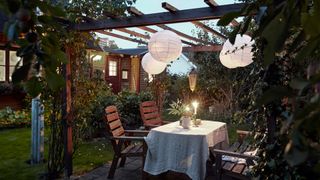 Backyard patio ideas: An image showing a table dressed in white linens placed under a dark wood pergola