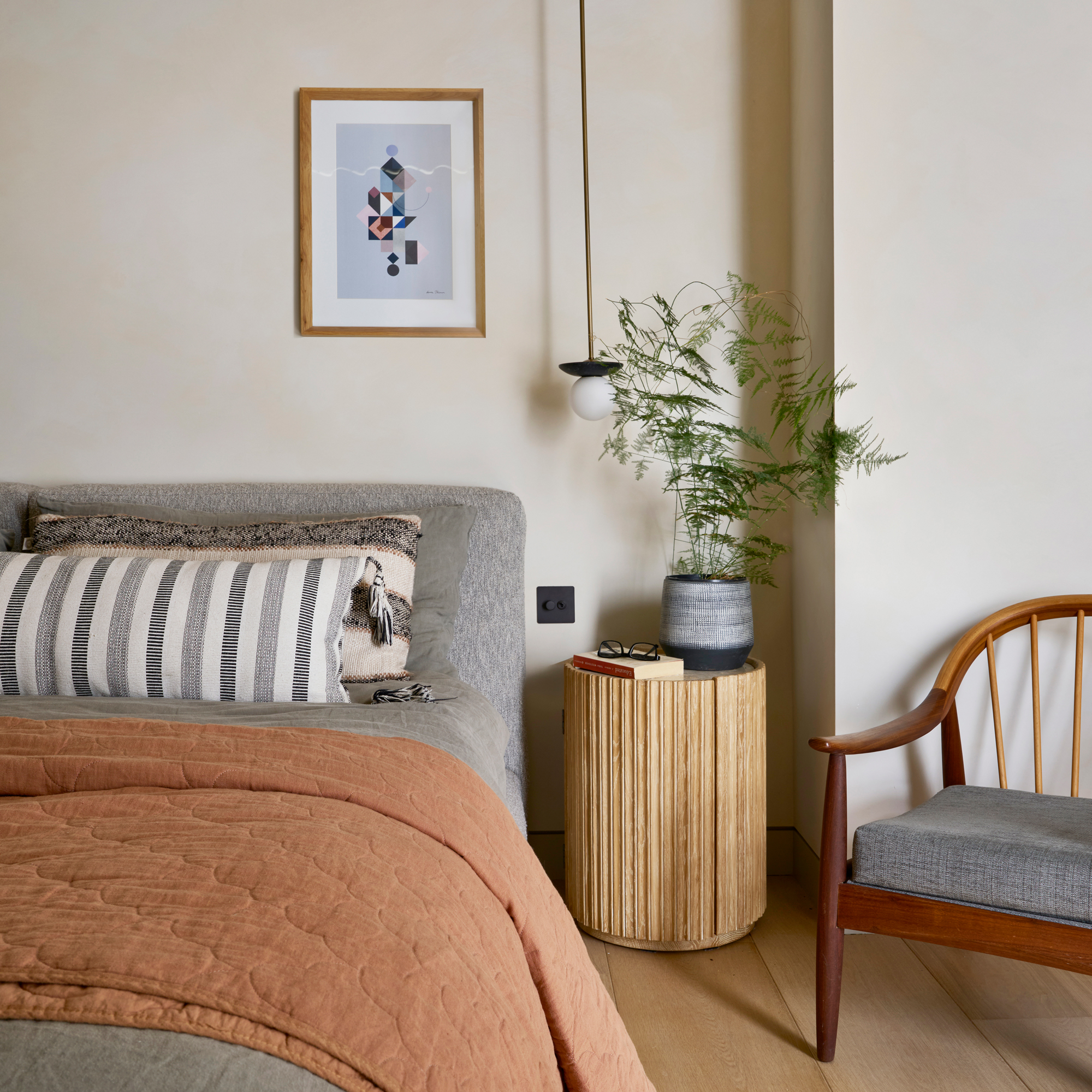 bedroom with grey upholstered bed and pendant lighting