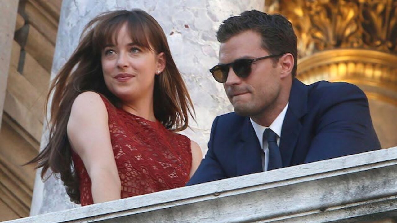 Anastasia and Christian look out from a balcony in 50 Shades of Grey