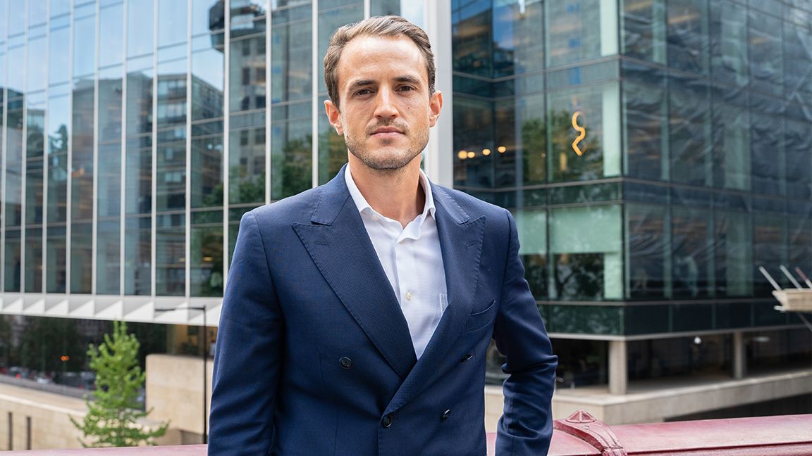 NFT art is on the way up; a man in a suit stands in front of a glass office block