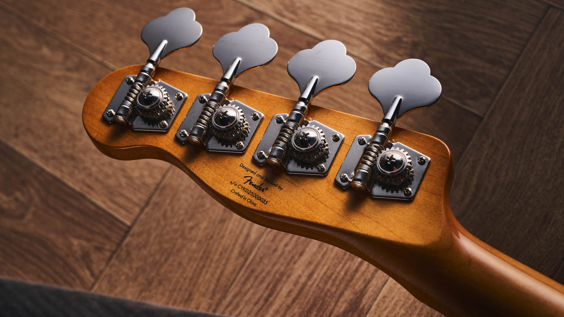 The Squier Classic Vibe Telecaster Bass is a fine-looking four-string in a custard-colored Vintage White, and is here photographed in close-up, against a plain wooden background. It has a single Wide Range humbucker.
