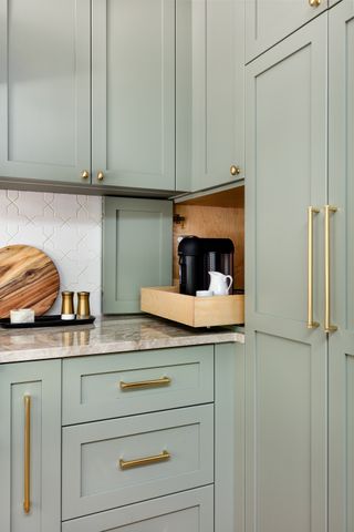 Sage green shaker style kitchen cabinets with a small appliance garage housing a coffee machine