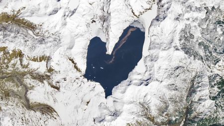 A satellite photo of a heart-shaped lake surrounded by snow