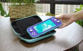 A photo of someone picking up a Switch Lite from a case