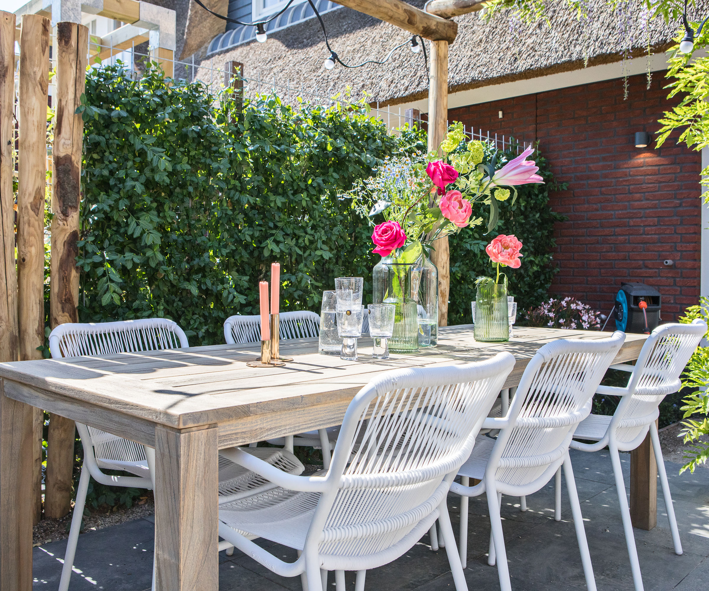 patio with table and chairs, flowers and candles, plus screening hedge of Euonymus
