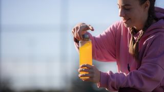 Woman opening bottle of orange sports drink