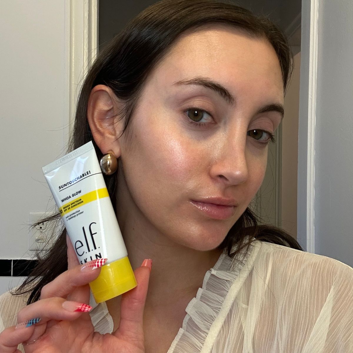 Associate beauty editor Alyssa Brascia holding a drugstore primer and a selfie of her wearing it.