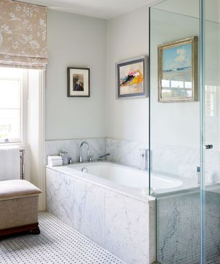neutral bathroom with bath with marble surround and neutral floral blind