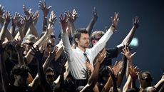 Harry Styles surrounded by dancers with raised hands as he performs on stage during The BRIT Awards 2026
