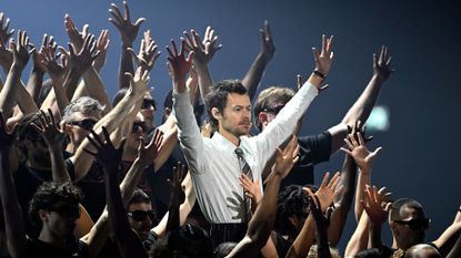 Harry Styles surrounded by dancers with raised hands as he performs on stage during The BRIT Awards 2026