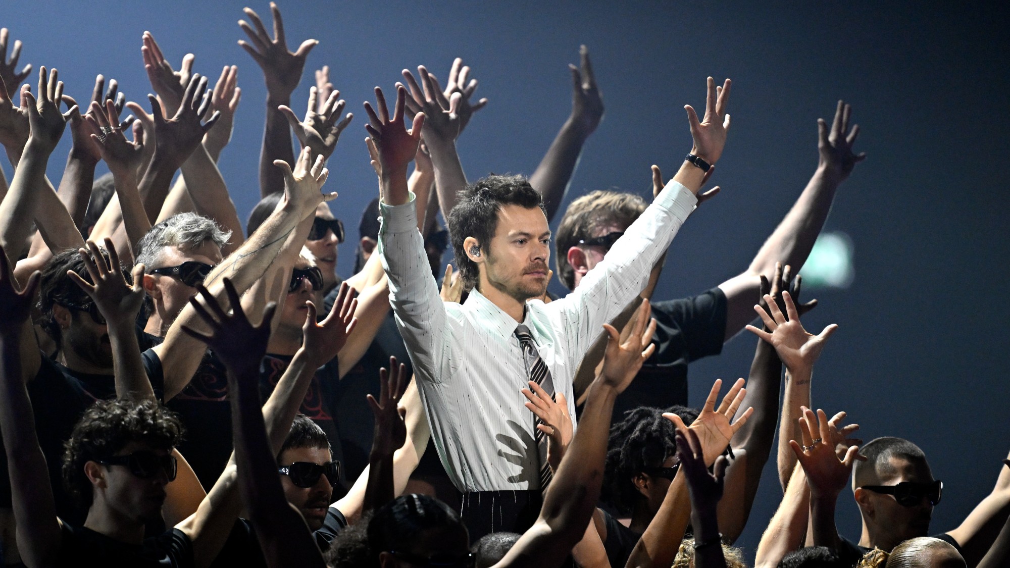 Harry Styles surrounded by dancers with raised hands as he performs on stage during The BRIT Awards 2026