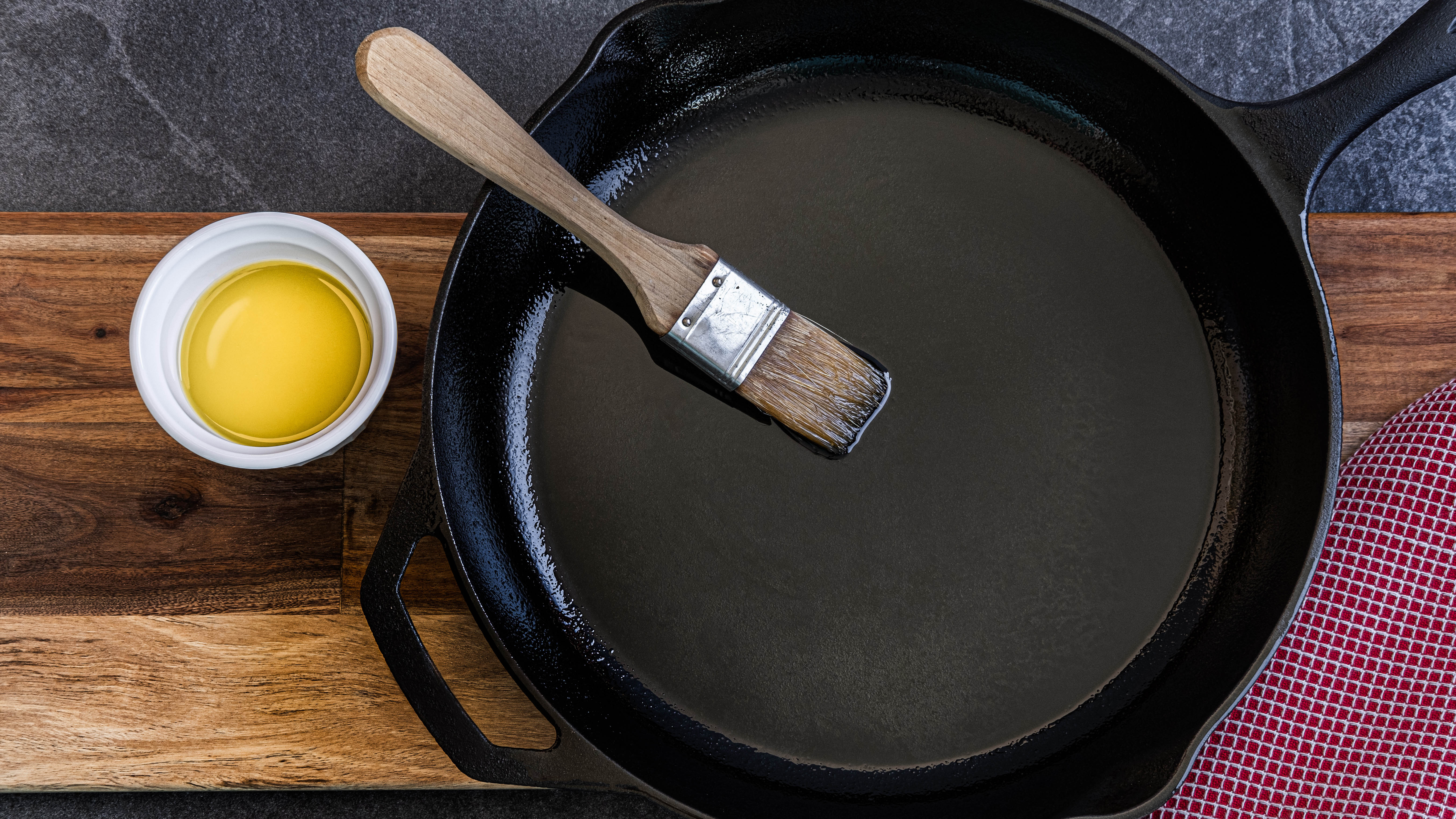 Чугунная сковорода смазывается маслом на деревянной поверхности