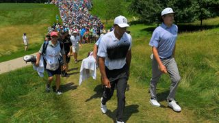 Joel Dahmen and Tiger Woods walk along the eighth hole with their gallery in tow during the third round of the Quicken Loans National at TPC Potomac at Avenel Farm on June 30, 2018 in Potomac, Maryland.