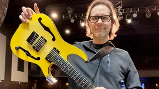 Paul Gilbert holding his missing Ibanez PGM1000T electric guitar