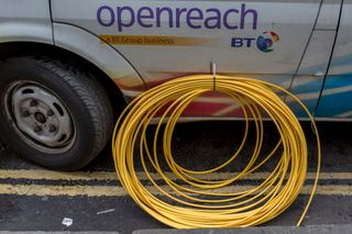 Detail of a BT Openreach van and a coil of yellow broadband fibre cable on the ground and awaiting installation