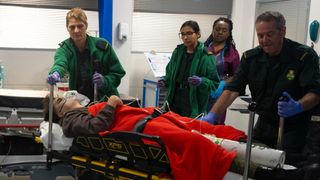 Mason on a hospital bed as Asha Alahan and an ambulance crew rush around him in Coronation Street.