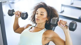 Best exercise for chest: Image shows young woman lifting dumbbells