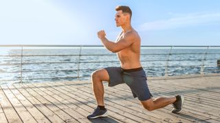 Man performing a lunge outdoors during workout next to the ocean