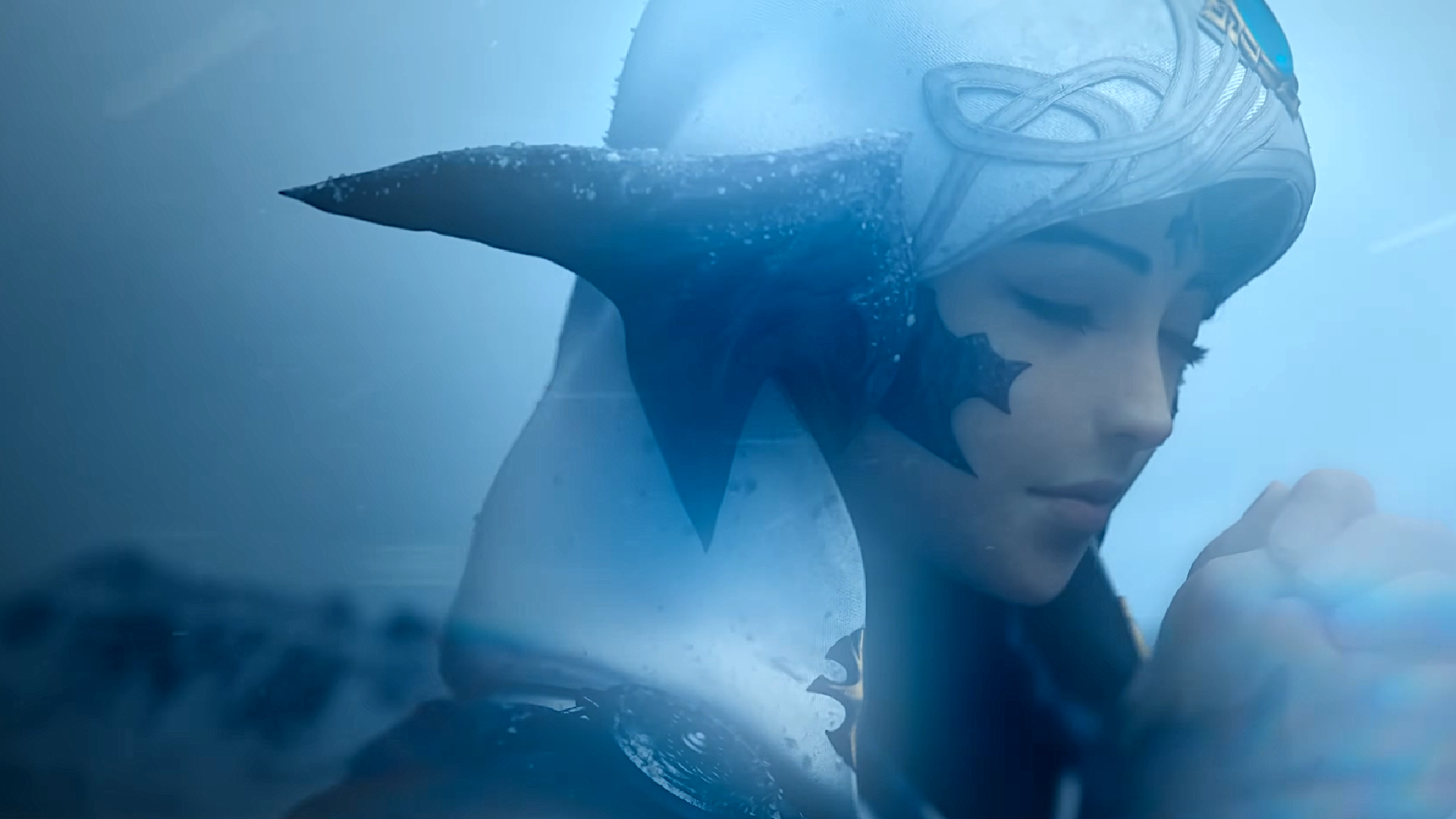 An au ra from Final Fantasy 14's evercold trailer kneels in the snow, praying as icy winds whip past her.