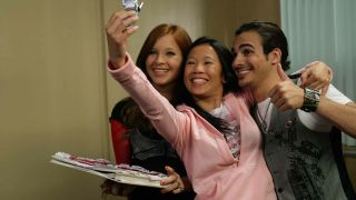 the cast of degrassi the next generation taking a selfie on a flip phone in a school hallway