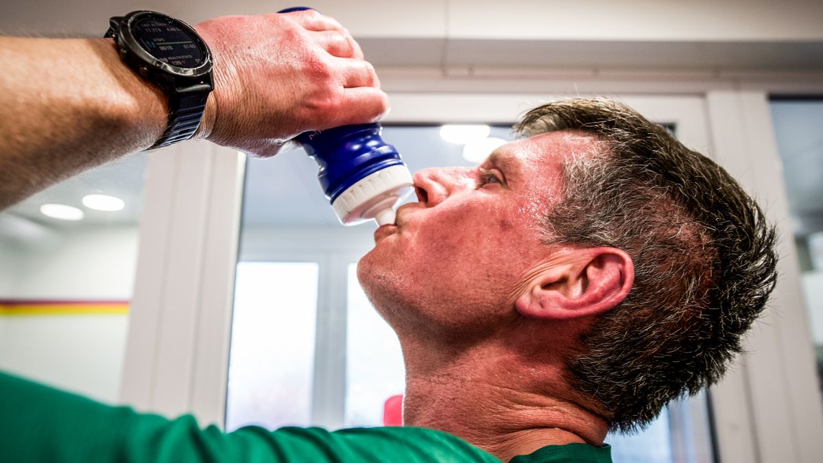 Sweaty runner rehydrates from a bottle after a session in a heat chamber