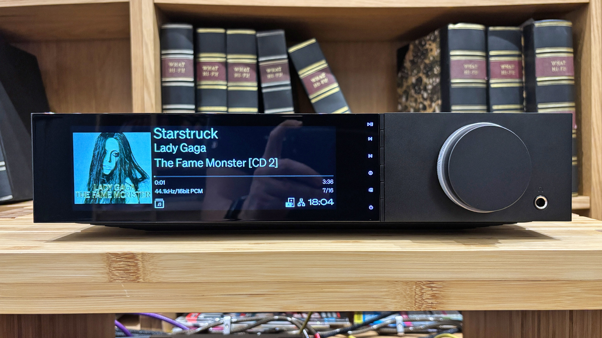 Cambridge Audio Evo 300 all-in-one system on wooden hi-fi rack in front of bookcase, on display is Lady Gaga