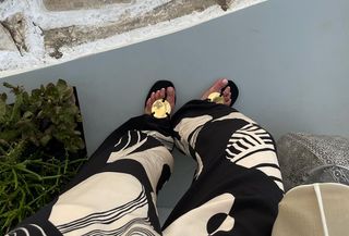 Anna Laplaca wearing Tory Burch gold-detail black flip flops on vacation.