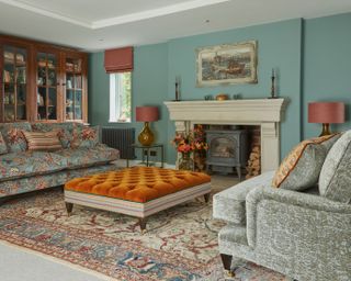 orange ottaman in a living room with walls painted light teal