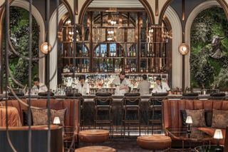 Bartenders wearing white jackets mix drinks behind the impressive bar at BKK Social Club