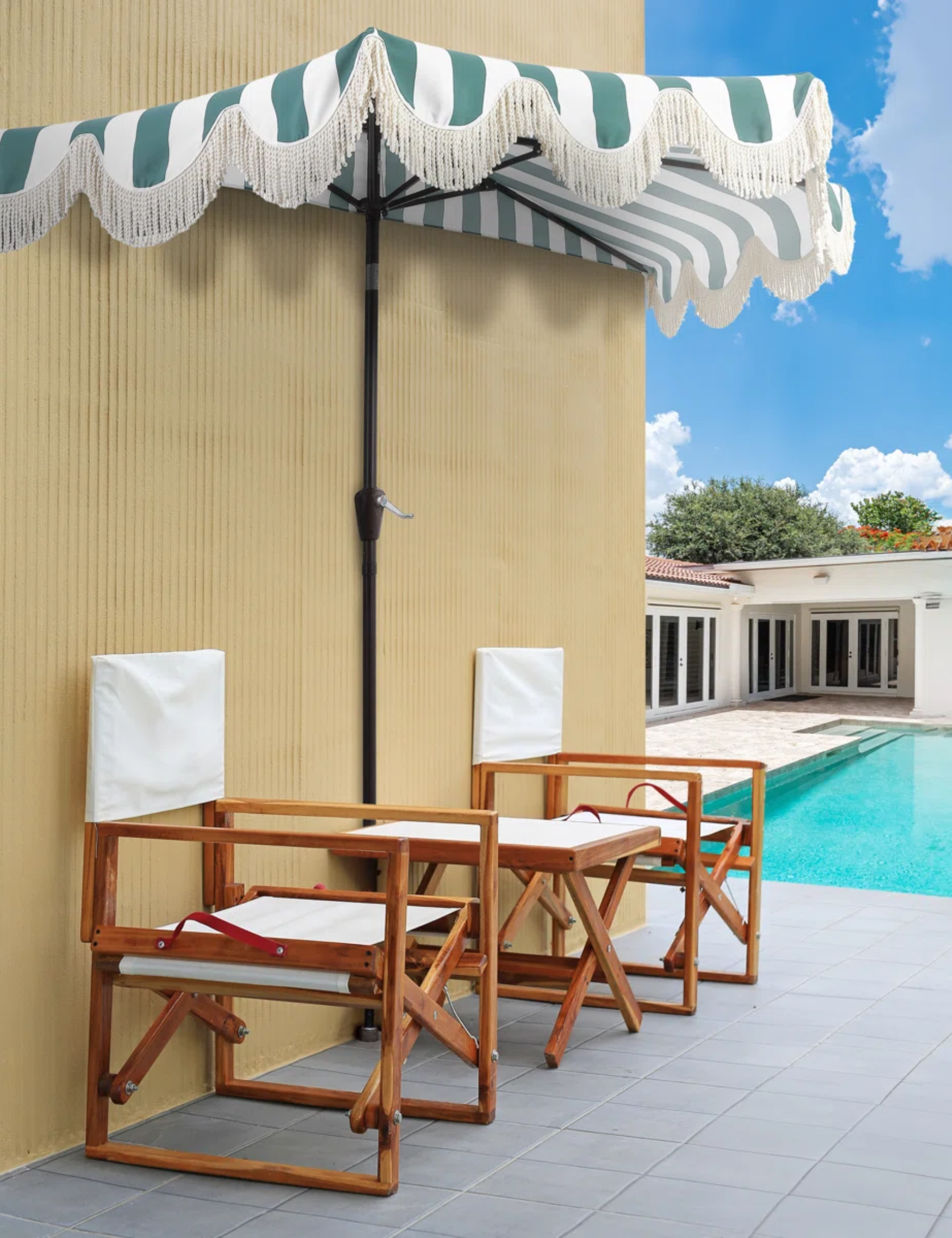 Striped half market umbrella with a bullion fringe scalloped border shading two wooden outdoor chairs beside a patio deck