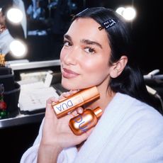 Dua Lipa holding her new DUA skincare products