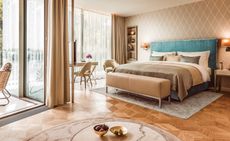 A bedroom at The Fontenay in Hamburg with a large bed, wooden floors, side tables, wall lamps and glass doors.