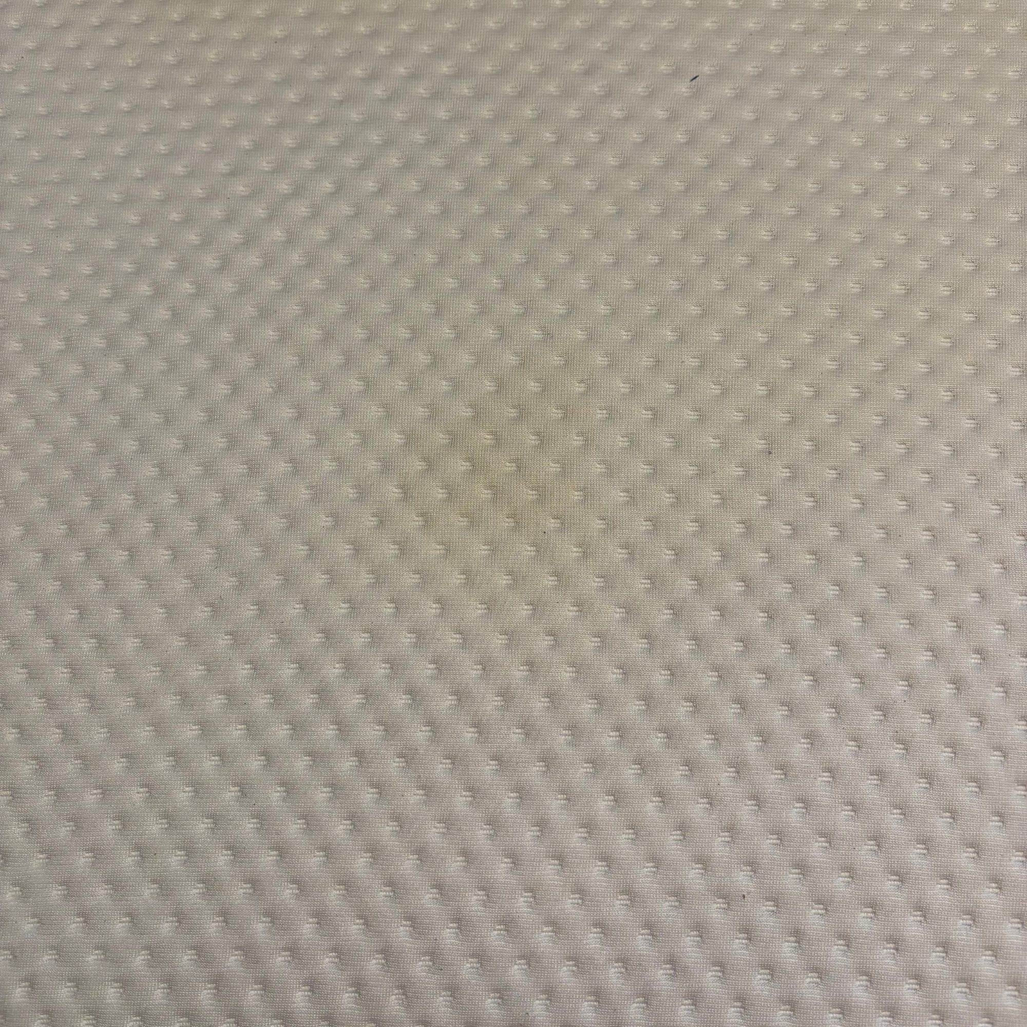 Quilted white / cream mattress fabric up-close before spot cleaner use