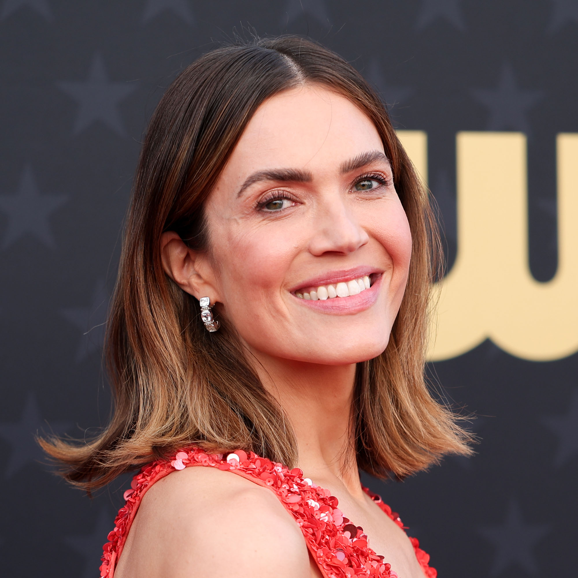 Mandy Moore wearing a red dress in front of black background at The 29th Critics' Choice Awards
