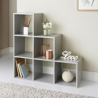 cream wall with shelving unit and flower on glass with books