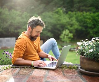 Man planning on a laptop in the backyard